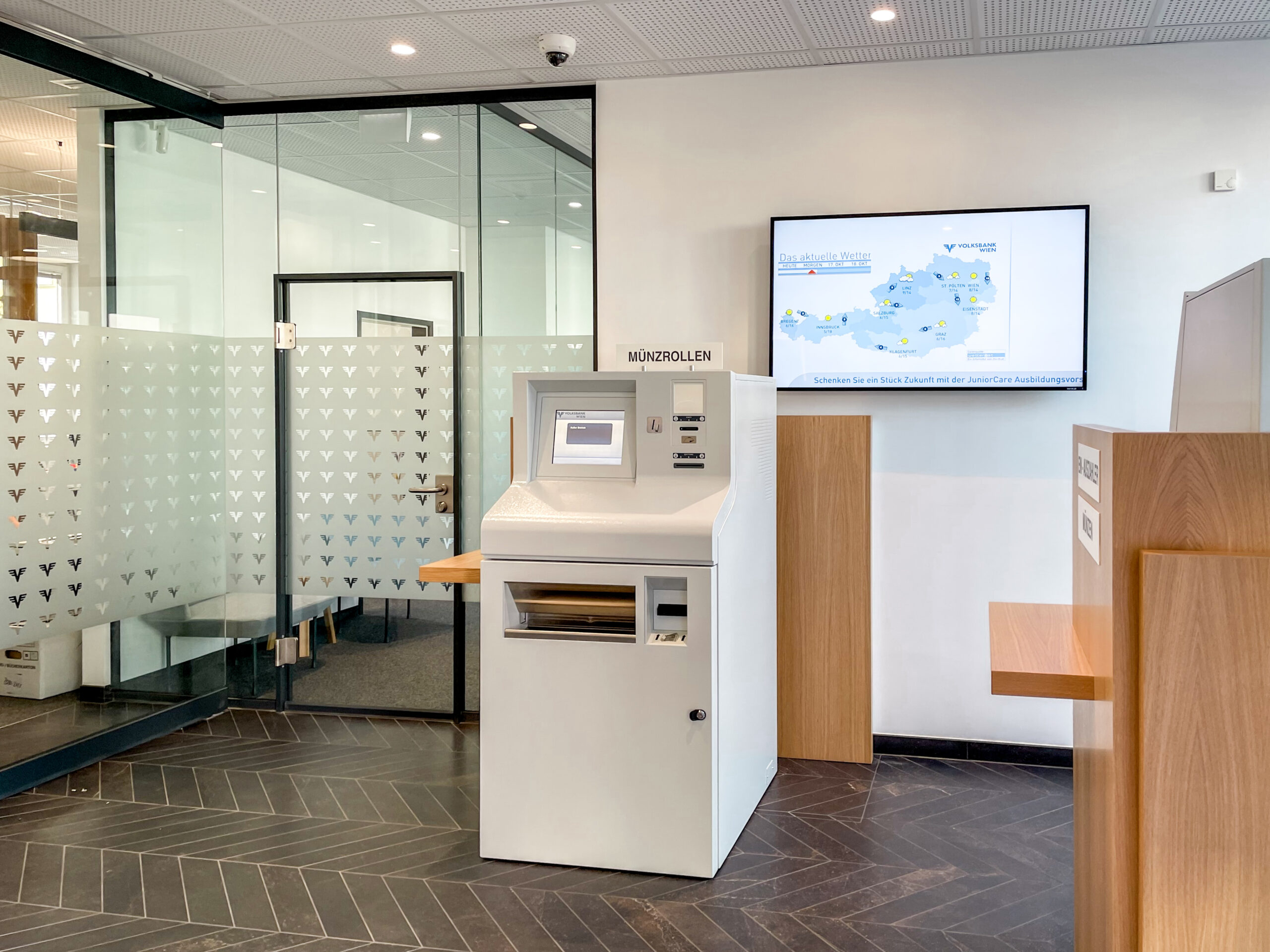Innenansicht der Volksbank Liesing mit Geldautomat und Infobildschirm.