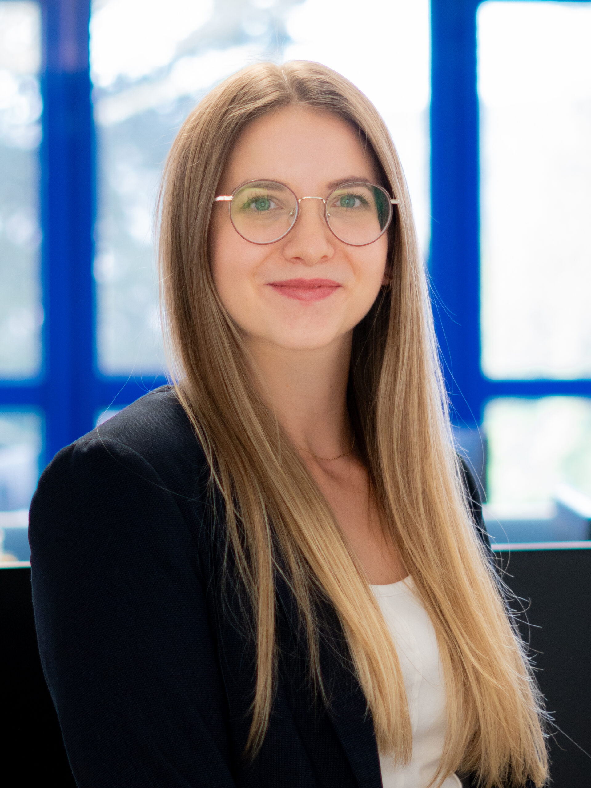 Über uns: Porträt einer blonden Mitarbeiterin mit Brille im Büro.